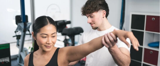 A physiotherapist at Physio Physique is assisting patient with stretches.